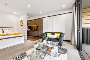 Ein modernes Wohnzimmer mit Sofa, Couchtisch und Blick auf eine Küche und einen Essbereich.