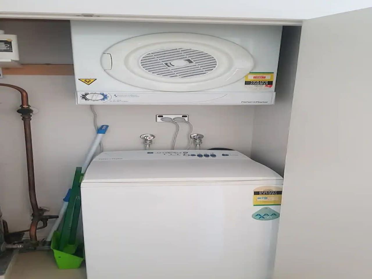 A compact, white washing machine with a front-loading door, a control panel with buttons, and a safety warning label.