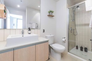 A modern bathroom with a large sink, toilet, and glass shower enclosure. - Wynyard Viaduct Harbour 2BR+Parking: Zodiak Stays (Auckland)