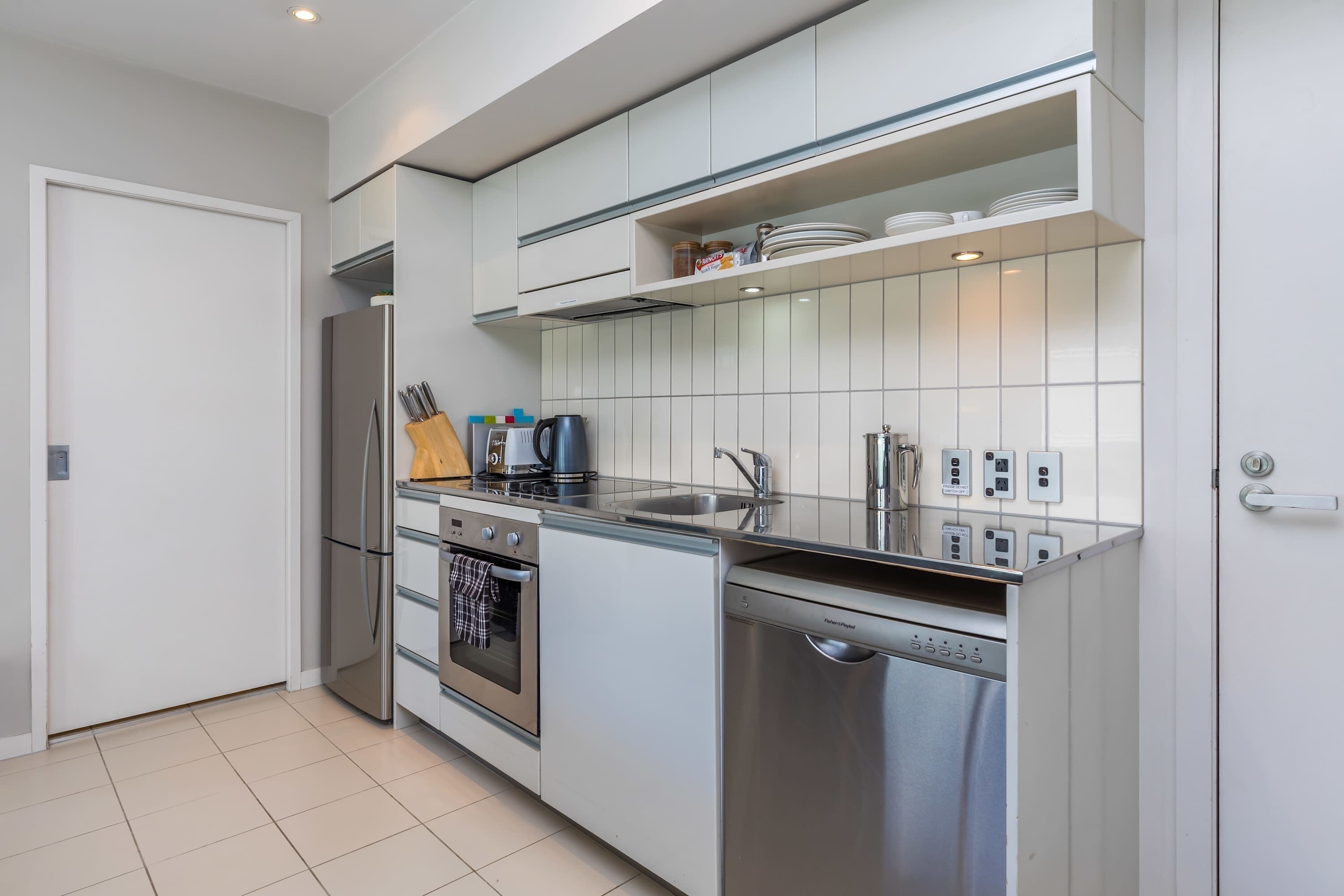 A modern kitchen with stainless steel appliances, a dishwasher, and a tiled backsplash.