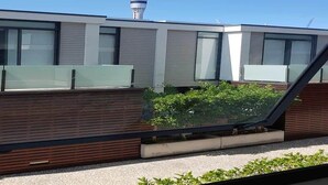 A modern building with large windows, a wooden facade, and a view of a tower in the background. - Wynyard Viaduct Harbour 2BR+Parking: Zodiak Stays (Auckland)