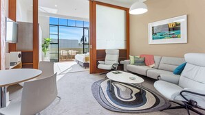Un salon moderne comprenant un canapé, des fauteuils, une table basse et un coin repas avec une table et des chaises.