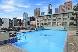 Una piscina en la azotea con vistas al horizonte de una ciudad, incluyendo un edificio del Banco de China.