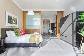 Ein modernes Schlafzimmer mit Bett, Nachttisch, Kleiderschrank und Blick in den angrenzenden Raum.
