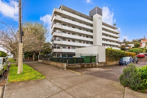 A multi-story building with a flat roof, numbered 44, and a gated parking area. - Lovely 2-Bedroom Rental with Parking by Zodiak (Auckland)