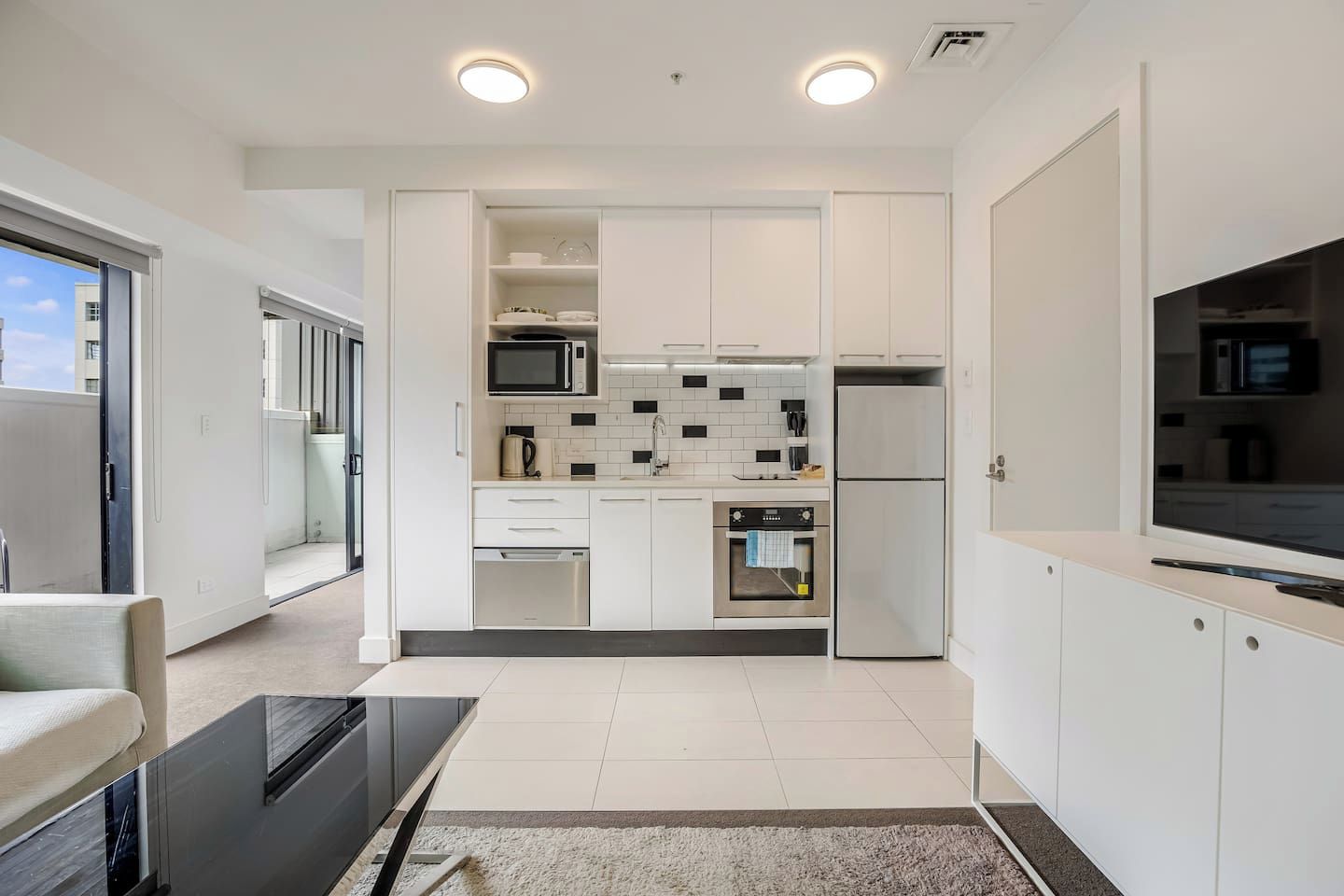 A modern kitchen with white cabinets, a microwave, a refrigerator, and a dishwasher.