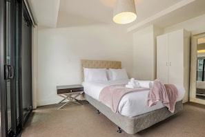 Ein Schlafzimmer mit Bett, Nachttisch, Kleiderschrank und einer Pendelleuchte.