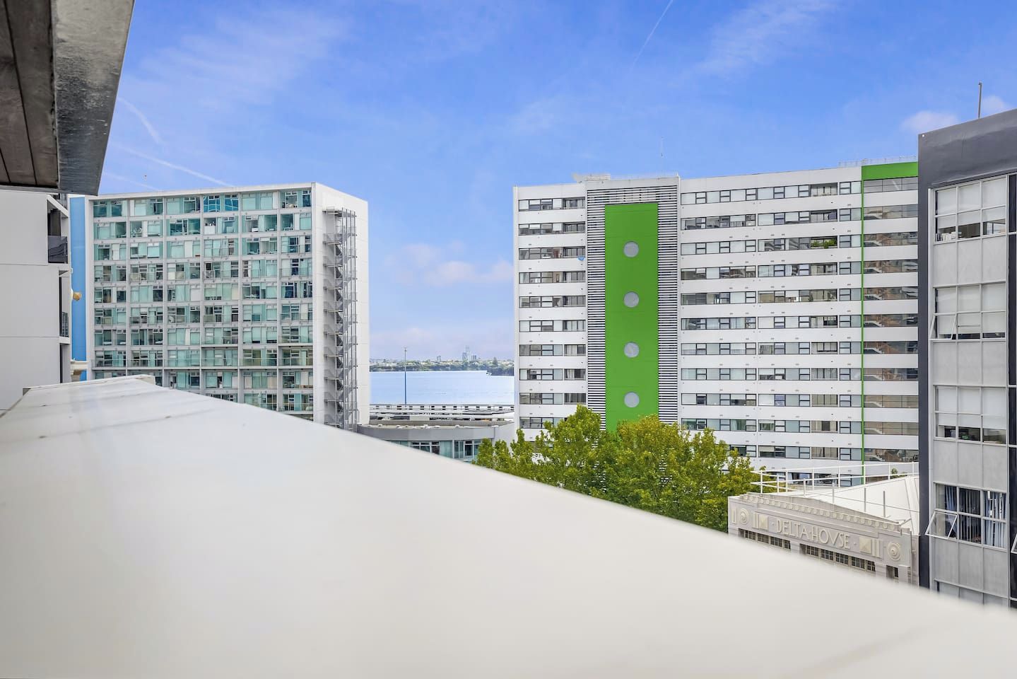 Un edificio moderno con varios pisos, grandes ventanales y un llamativo elemento vertical verde.
