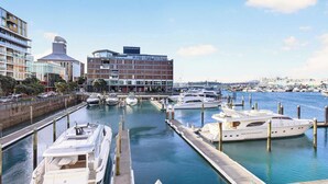 A marina with several yachts docked, a modern building with a sign reading 'Park Hyatt,' and a waterfront promenade. - Gorgeous 2BR in Wynyard Quarter by Zodiak Stays (Auckland)