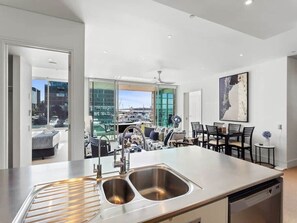 Eine moderne Küche mit doppelter Spüle, einem Essbereich mit Tisch und Stühlen sowie Blick auf die Stadt durch große Fenster.