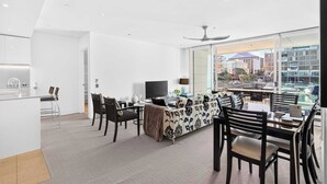 A modern living room with a sofa, chairs, a dining table, and a TV. - Gorgeous 2BR in Wynyard Quarter by Zodiak Stays (Auckland)