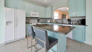 Una cocina moderna con armarios color turquesa, encimera de granito y electrodomésticos de acero inoxidable.