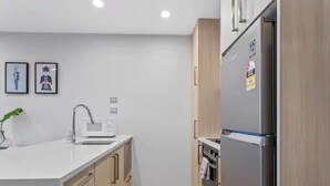 A modern kitchen with a white countertop, stainless steel appliances, and wooden cabinets. - Stunning 2BR w/ Views Near Sky Tower- Zodiak Stays (Auckland)