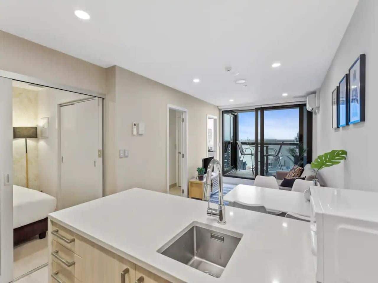 A modern kitchen with a large island, a built-in sink, and a view to the living area.