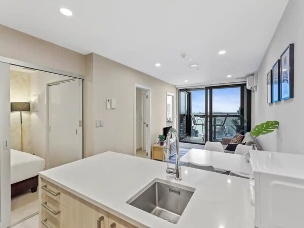 A modern kitchen with a large island, a built-in sink, and a view to the living area.