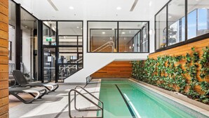 A swimming pool area with a wooden wall, a staircase, and a view of the interior. - Sky Tower Views | 2 Bed 2 Bath CBD | Zodiak Stays (Auckland)