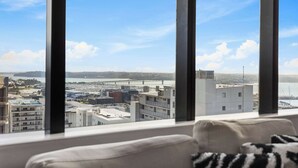 A high-rise room with a large window offering a city view. - Sky Tower Views | 2 Bed 2 Bath CBD | Zodiak Stays (Auckland)