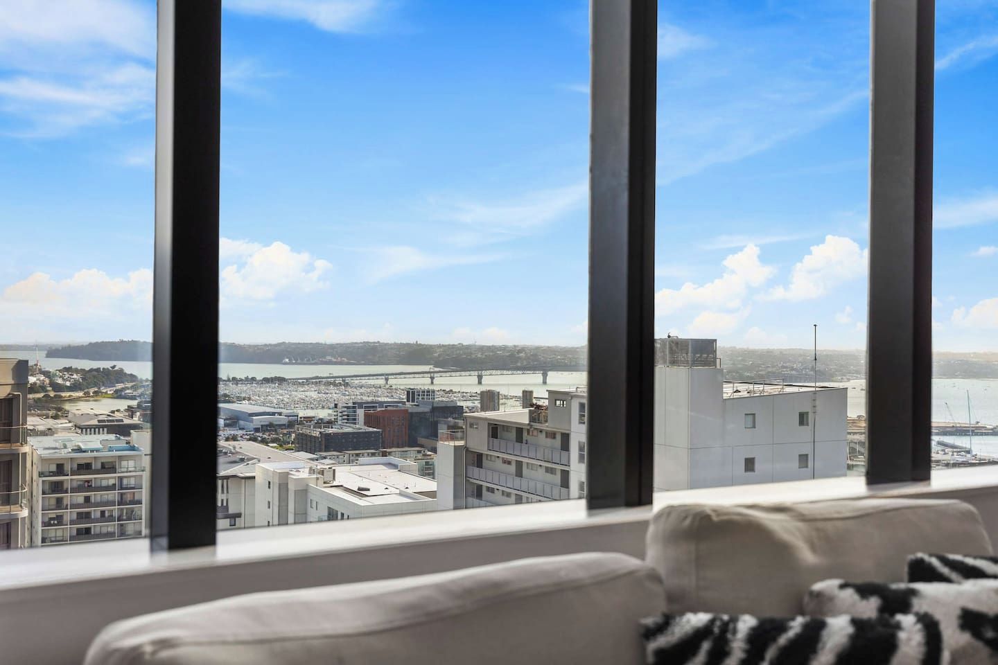 A room with a large window overlooking a cityscape, including buildings and a body of water.