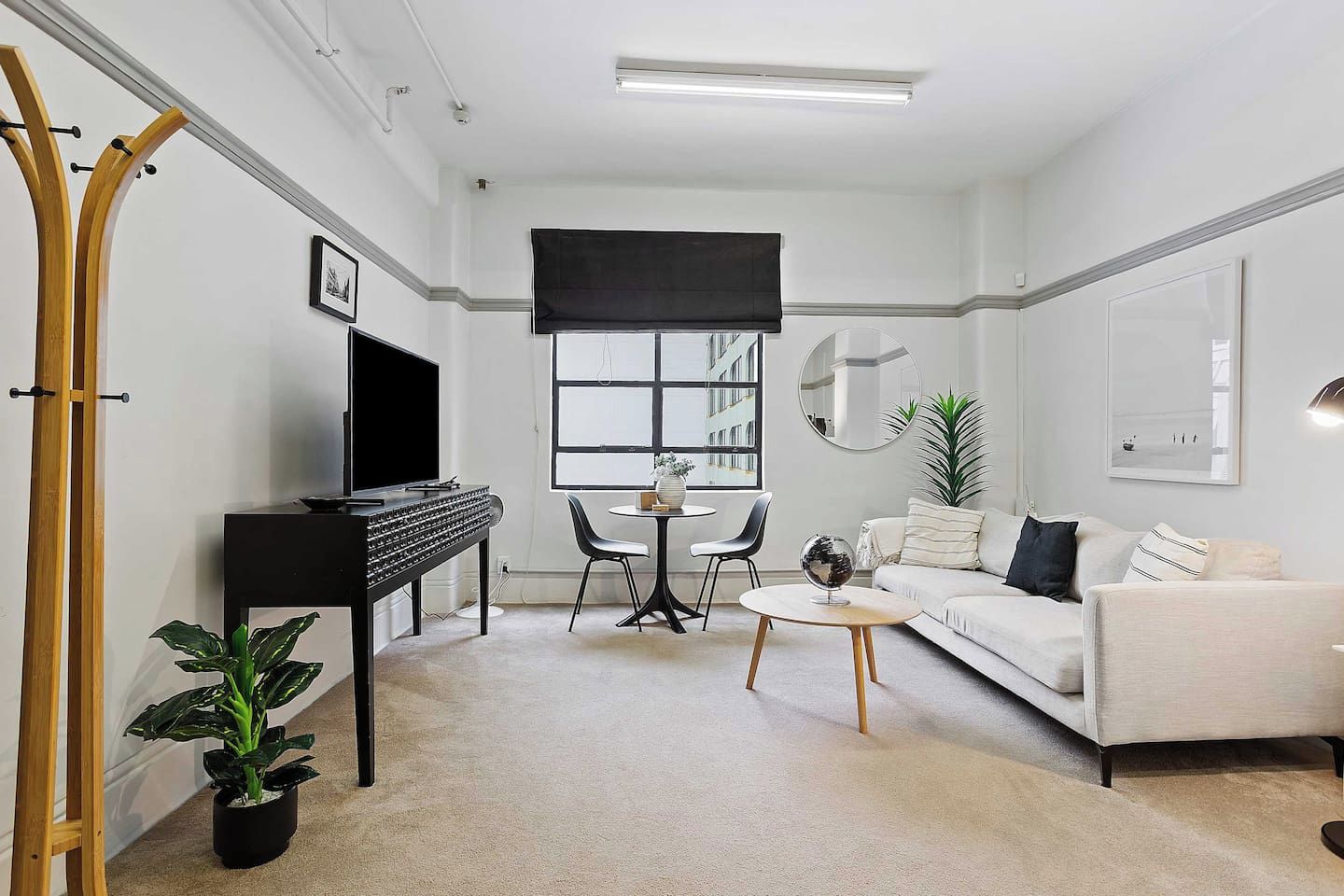 A modern living room with a sofa, a coffee table, a TV, and a dining area with chairs.