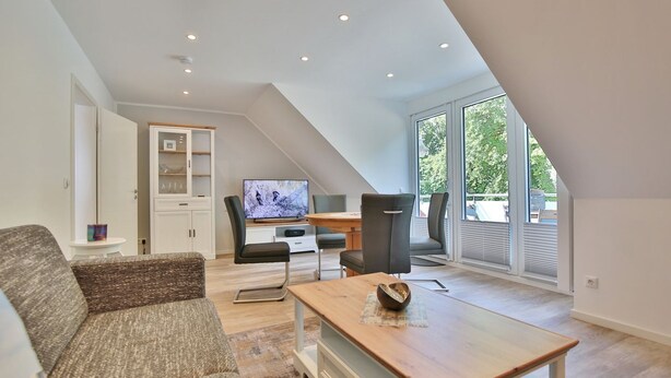 Un loft moderno con comedor, televisor y un amplio ventanal.