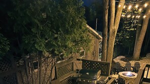 Un patio trasero con jacuzzi, parrilla y zona de estar.