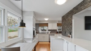 Una cocina moderna con armarios blancos, una mesa de comedor de madera y vistas al exterior.
