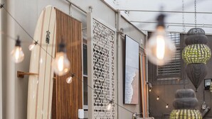 A cozy indoor space with a surfboard, a wooden slat wall, and a table with chairs. - London Plane Backpackers - Hostel (Potts Point)
