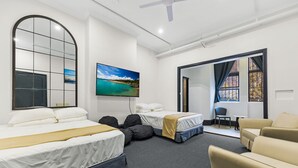 A hotel room with two beds, a TV, a large window, and a seating area. - London Plane Backpackers - Hostel (Potts Point)