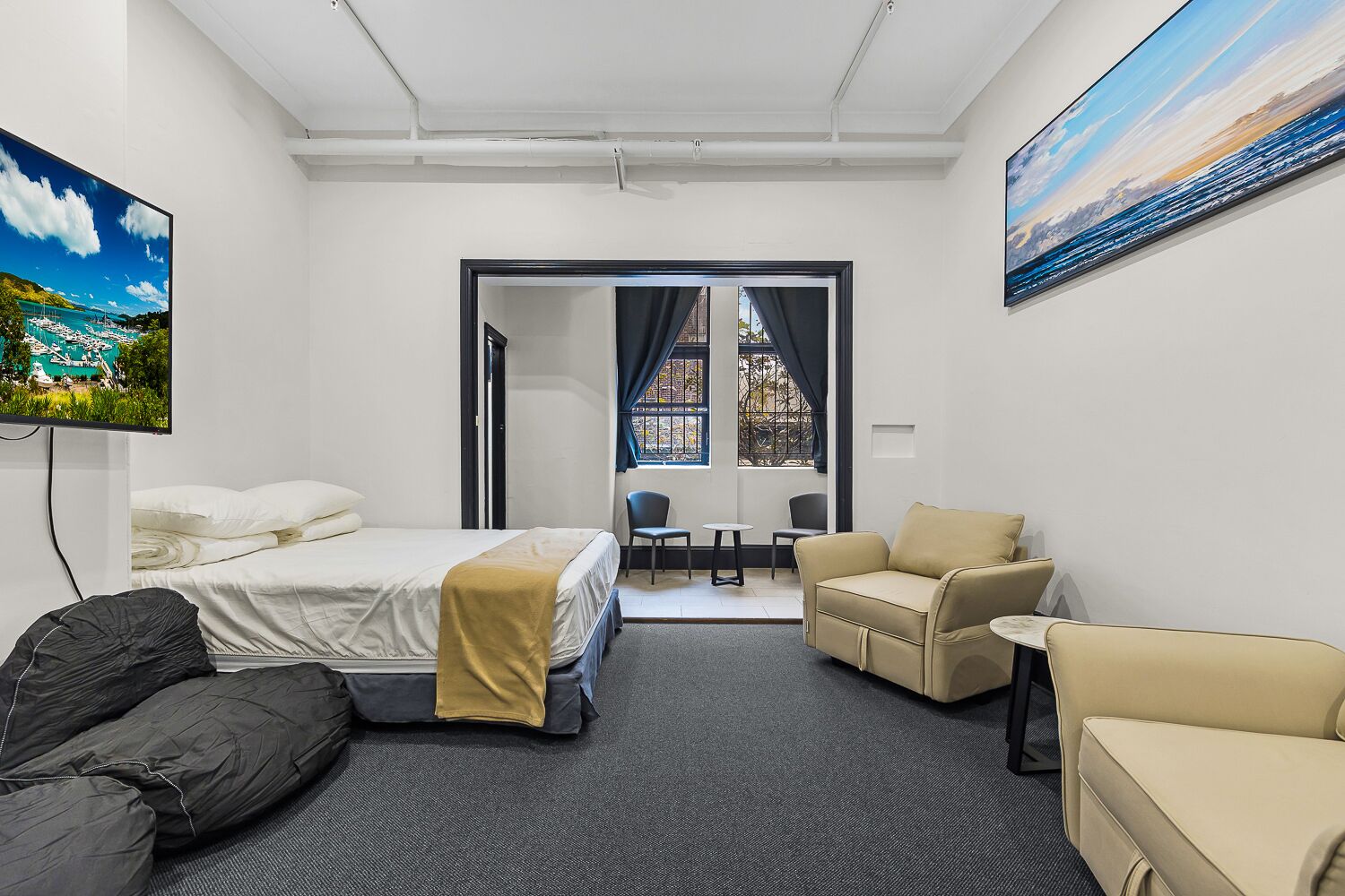 Una habitación de hotel con una cama, dos sillones, una mesita y un televisor.