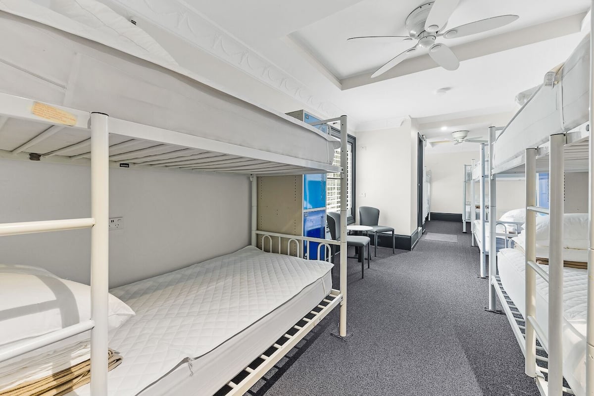 A bunk bed room with a ceiling fan, a desk, and a chair.