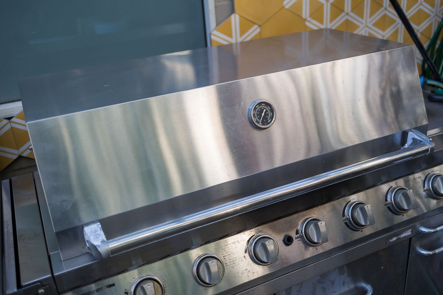 A stainless steel grill with a control panel and knobs.