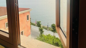 Uma janela com vista para uma área costeira, incluindo um edifício e um céu claro.