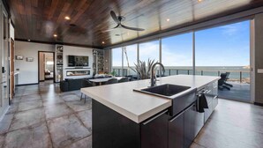 Una cucina moderna con una grande isola, un ventilatore a soffitto e vista sull'oceano.
