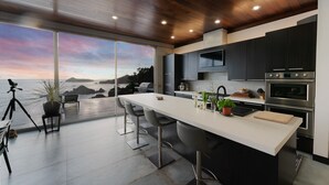 Una cucina moderna con un'isola grande, elettrodomestici in acciaio inossidabile e vista sull'oceano.