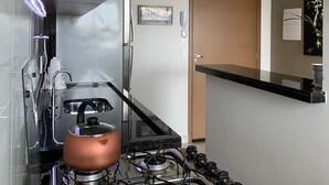 Une cuisine moderne dotée d’une cuisinière à gaz, d’appareils électroménagers en acier inoxydable et d’un plafond en bois.