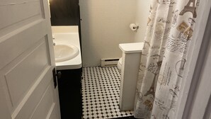 A bathroom with a white sink, a toilet, and a shower curtain with Paris-themed prints. - Main Street Crosby (Crosby)