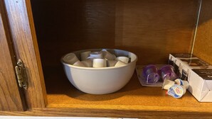 A kitchen cabinet with a white bowl containing various items, a coffee maker, and some coffee pods on the countertop. - Main Street Crosby (Crosby)