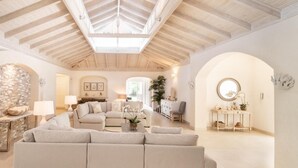 A spacious living room with a high wooden ceiling, a large sofa, and a stone wall.