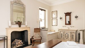 A room with a fireplace, a bed, a vanity with a mirror, and a window with a view. - A Chelsea Retreat - 2 BR with Garden and Parking (London)