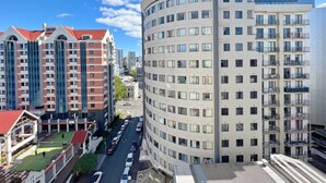 A high-rise building with multiple floors, a curved corner, and a flat roof. - Sky Tower View Studio in CBD (Auckland)