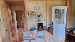 Un interior de madera con una isla central, una cafetera y una puerta con ventanal.