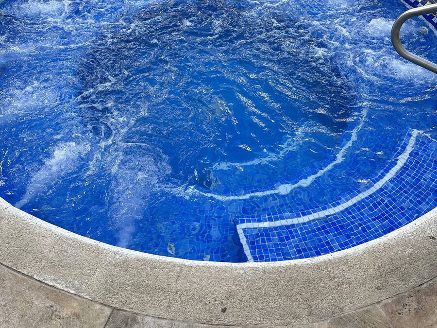 A circular pool with a tiled edge, surrounded by a stone deck.