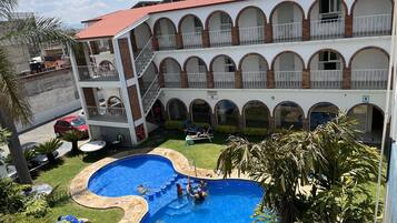 Un edificio de varios pisos con piscina, mobiliario exterior y un patio cubierto.