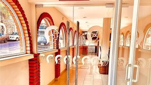 A hotel corridor with tiled flooring, red brick walls, and glass doors leading to a room. - Hotel el Romano Ixtapan de la Sal  (Ixtapan de la Sal)