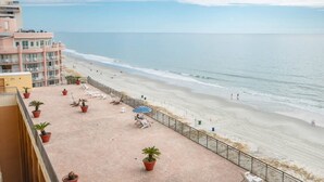A beach view from a balcony with potted plants and lounge chairs. - Oceanfront | Amazing Views & Sunrises (Myrtle Beach)