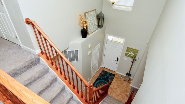 Una escalera con barandillas de madera que conduce a un rellano con una puerta y una alfombra decorativa.