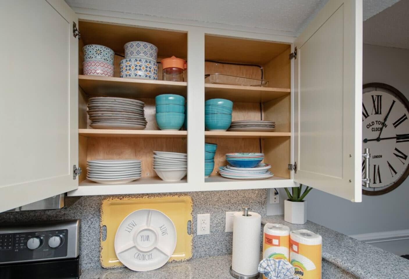 Un meuble de cuisine contenant différents plats et une horloge.