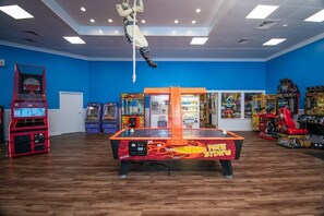 A room with a basketball hoop, arcade games, and a table tennis table.