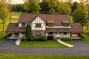A two-story house with a front porch, a driveway, and a well-maintained lawn. - Roomy Beautiful Golf/Ski Condo (Clymer)