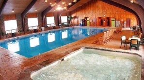 An indoor swimming pool with a hot tub, wooden walls, and seating areas. - Roomy Beautiful Golf/Ski Condo (Clymer)